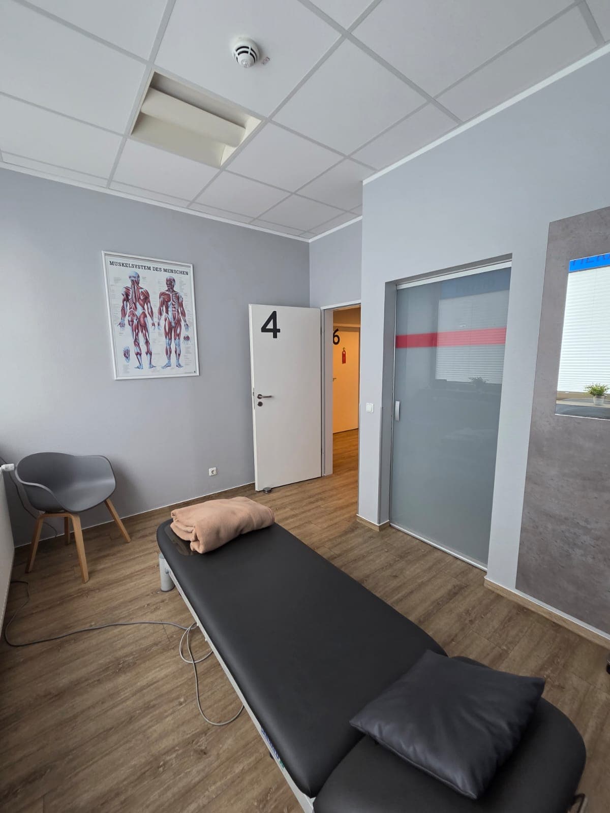 Behandlungsraum mit Therapieliege und Anatomie-Poster